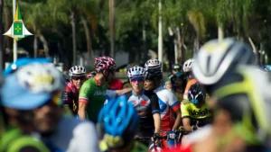 foto de dezenas de ciclistas com capacetes e vestidos com roupas de ciclistas, que aguardam a largada da prova.