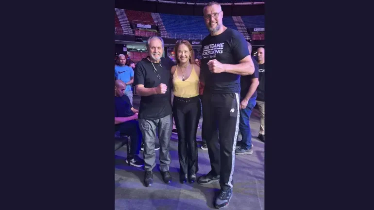 foto da tetracampeã de karate Carla Ribeiro, vestindo blusa de alça amarela, colar dourado e calça preta, o Mestre Testa, vestindo uma blusa preta e calças cinza, e o tetracampeão do K1 Semmy Schilt, vestindo uma camiseta preta onde se lê FIGHT GAME - ACADEMY -KICKBOXING -SEMMY SCHILT e calças de agasalho preta com listas laterais.