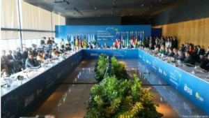 foto de uma reunião com governadores em dezembro de 2024 em Brasília. Sentados em várias mesas que formam a letra "U" com toalhas azuis e um painel azul atrás da ponta dessa formação estão vários homens e 4 mulheres sentadas, tendo atrás de si vários assessores sentados em cadeiras.