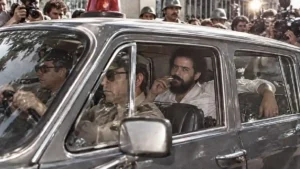 imagem de homem barbudo fumando no banco de trás do carro dirigido por militares, na década de 80.